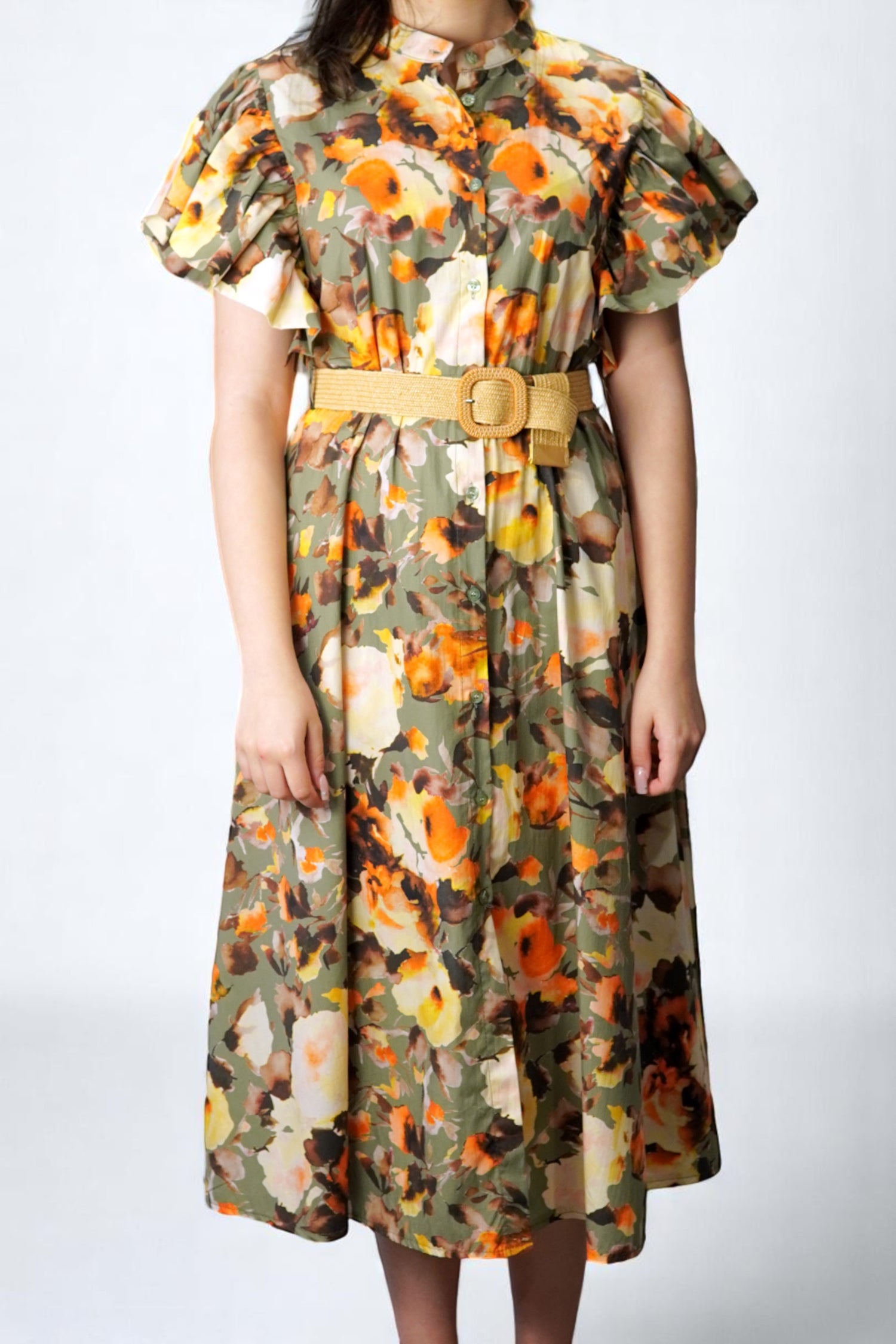 Rochie florală în tonuri de olive și portocaliu, cu volane elegante la umeri și curea decorativă.