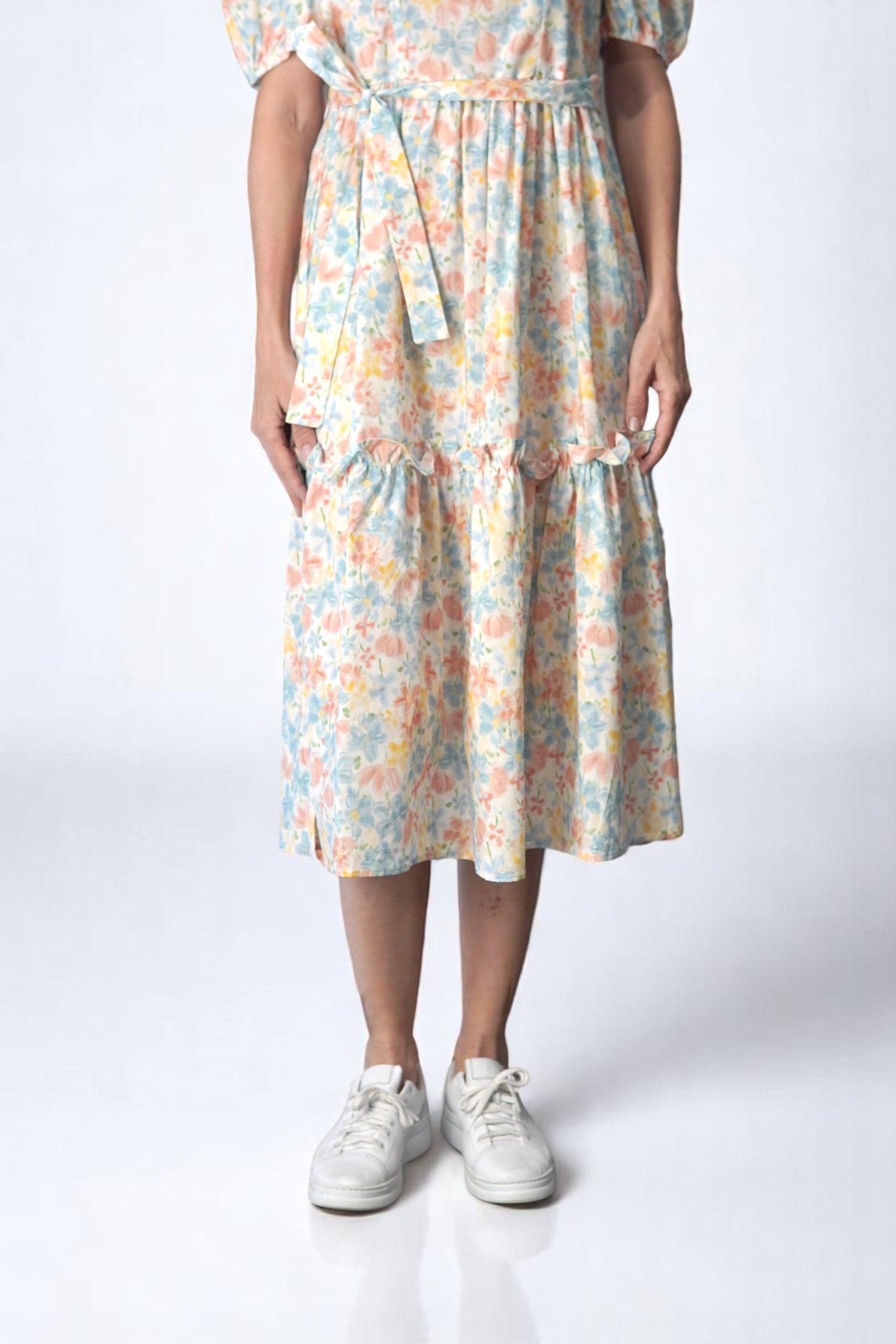 Tivul rochiei midi cu imprimeu floral pastel, evidențiat prin volane discrete.
