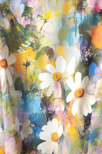 Detaliu de material al unei rochii florale, cu flori mari stilizate în nuanțe pastel și textură fină, ușor satinată