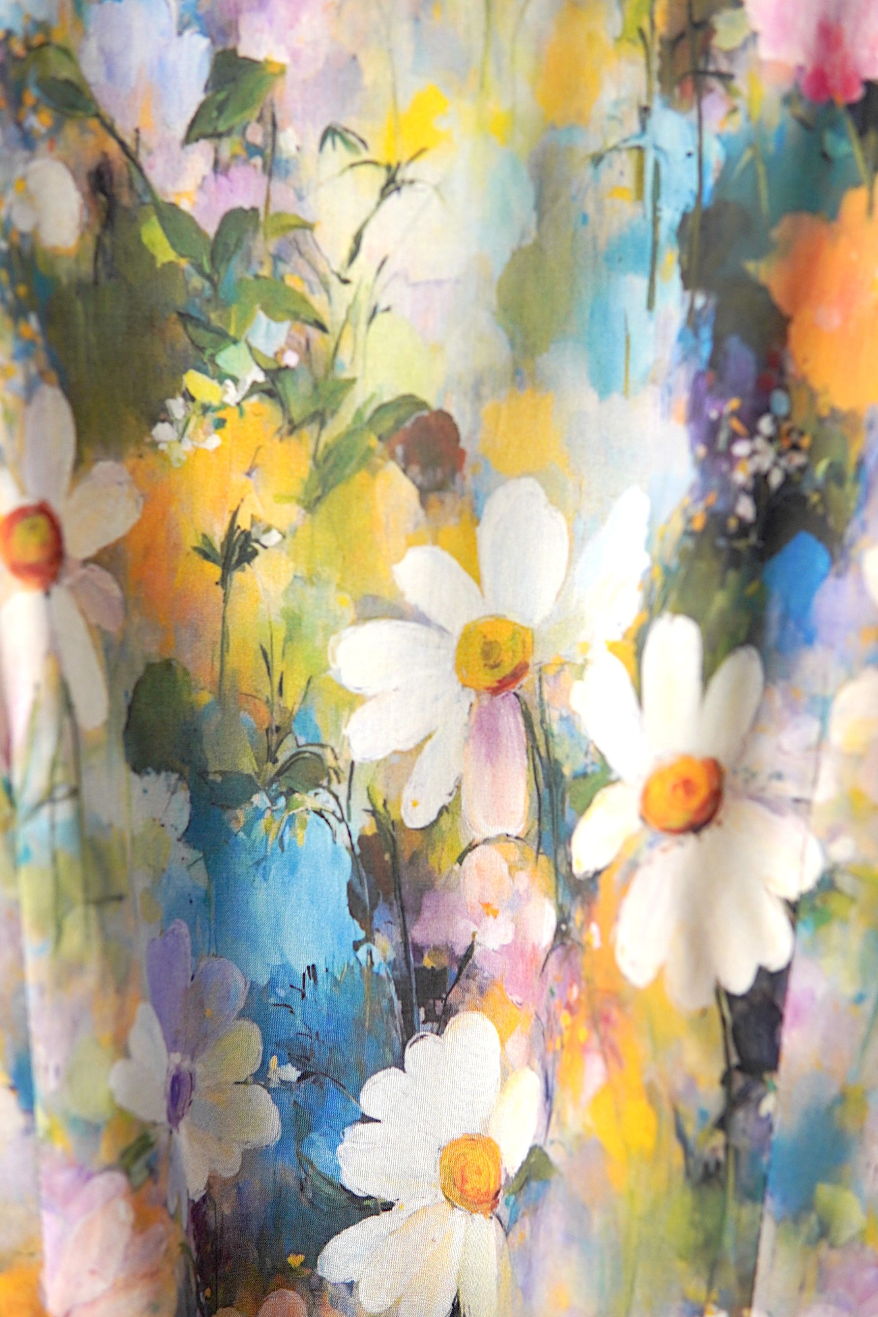 Detaliu de material al unei rochii florale, cu flori mari stilizate în nuanțe pastel și textură fină, ușor satinată