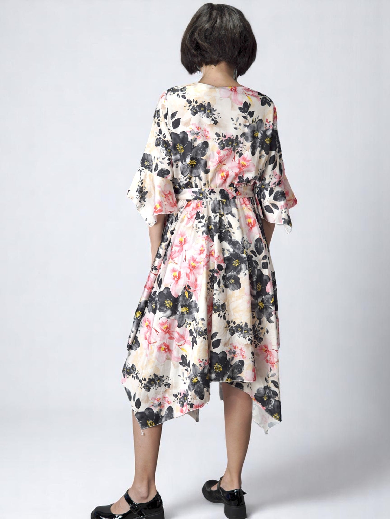 Rochie florală pe fundal negru, vedere din spate, cu tiv asimetric