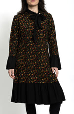 Rochie midi cu floricele, mâneci lungi și guler cravată, purtată cu dresuri negre, stil feminin de zi.