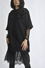 Rochie neagră tip hanorac, cu aplicație floare 3D pe umăr și tiv din dantelă, fotografiată din față.