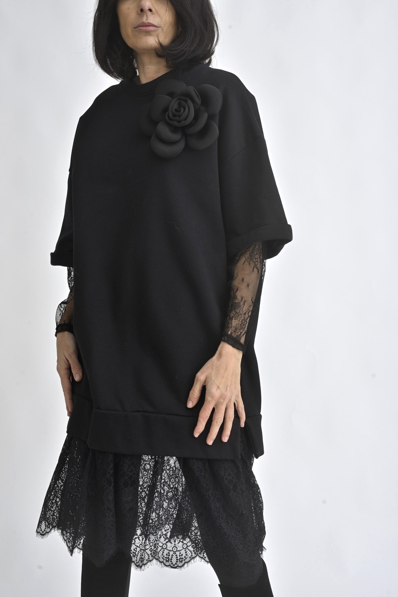 Rochie neagră tip hanorac, cu aplicație floare 3D pe umăr și tiv din dantelă, fotografiată din față.