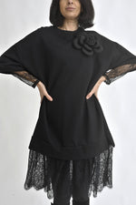 Vedere laterală a rochiei negre tip hanorac, cu mâneci largi și inserție din dantelă la tiv.