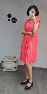  Rochie scurtă în nuanță roz coral, plisată pe toată lungimea, cu look feminin și fluid.