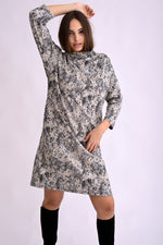 Rochie tricotată cu imprimeu abstract și guler înalt, croială dreaptă și umeri căzuți, vedere laterală pe model.