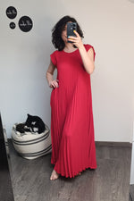 Rochie roșie plisată, privire frontală, cu croială lejeră și umeri căzuți, purtată de model în fața oglinzii.