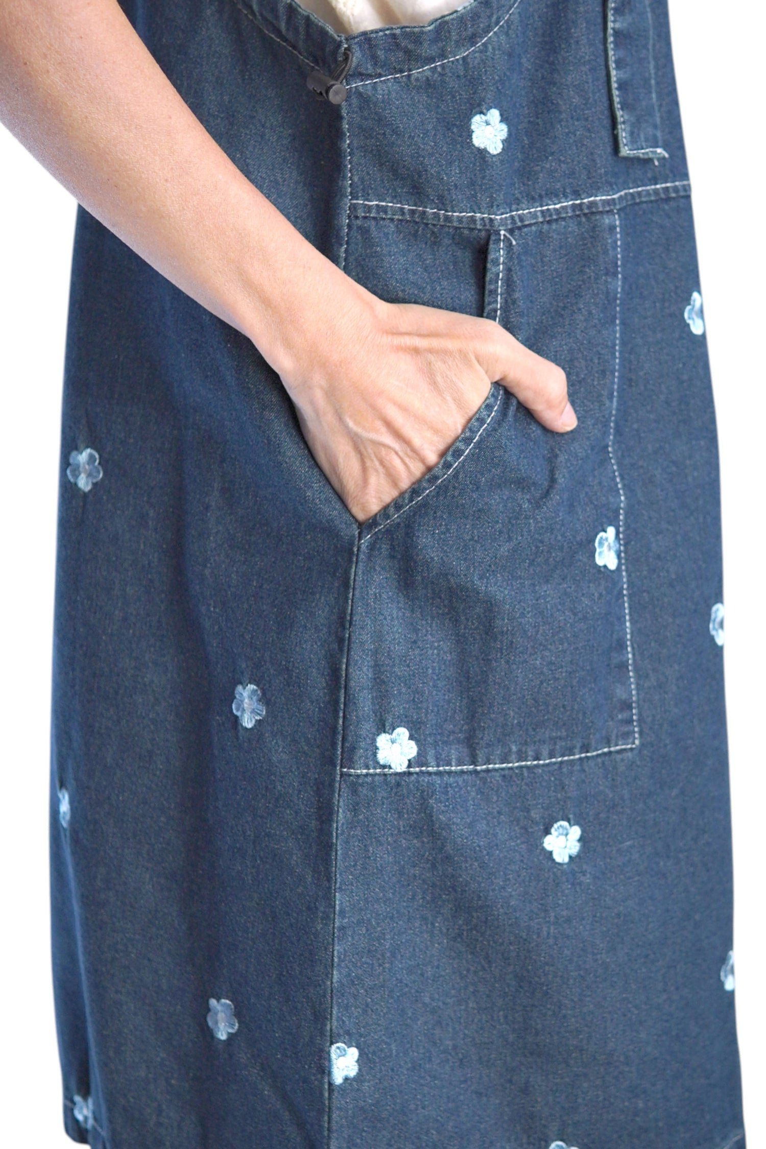  Detaliu lateral al buzunarului aplicat pe rochie din denim brodat, cu mână în buzunar.