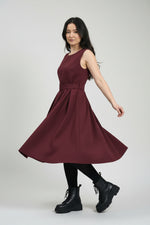 Rochie sarafan bordo cu pliuri fluide, surprinsă în mișcare, evidențiind volumul fustei.
