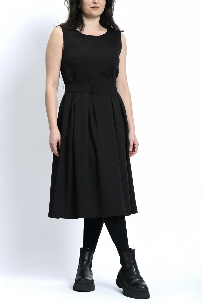 Rochie sarafan neagră cu pliuri, purtată cu bocanci, stil urban și echilibrat.