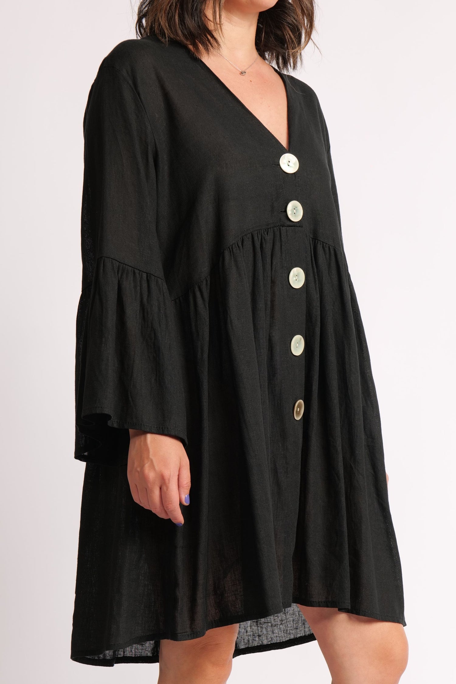 Rochie scurtă din in neagră, decolteu în V și croială lejeră, purtată de model.