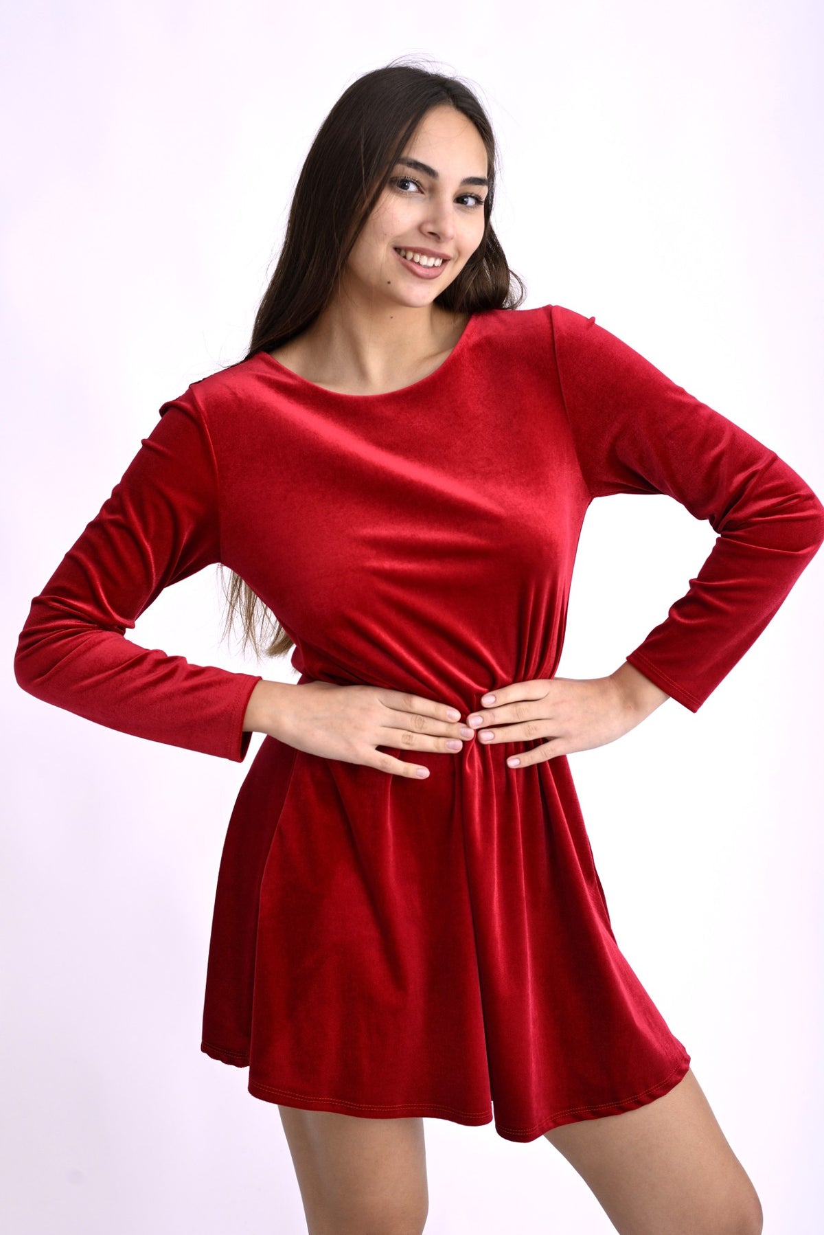 Rochie scurtă roșie din catifea cu mâneci lungi, evidențiind silueta feminină și textura luxoasă.