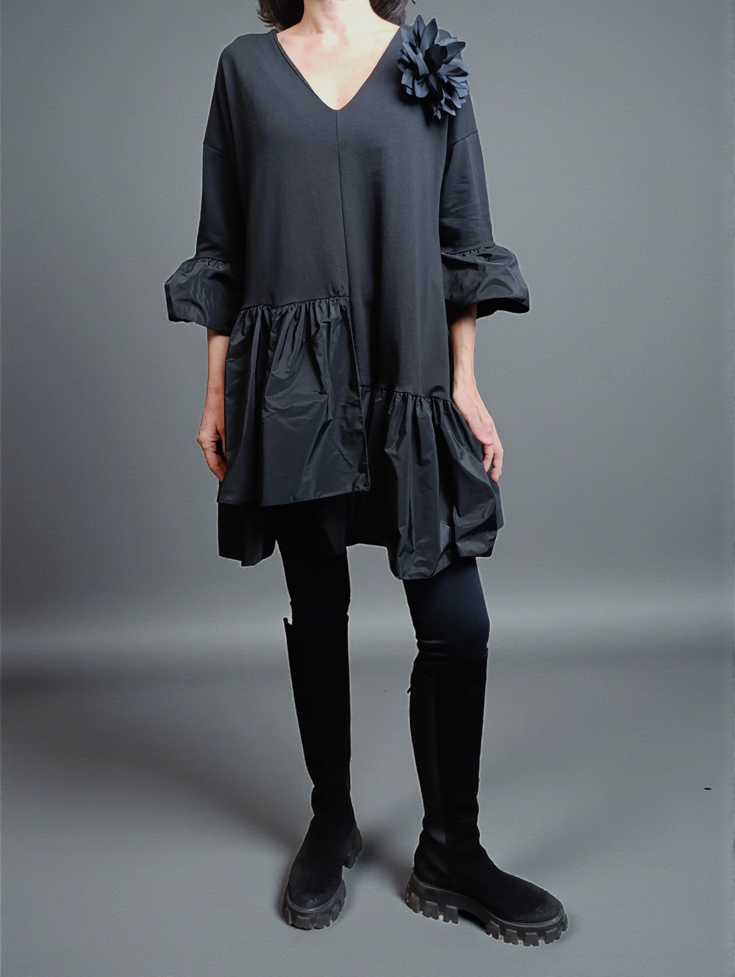 Detaliu rochie scurtă cu umeri căzuți, mâneci largi și aplicație florală pe umăr.