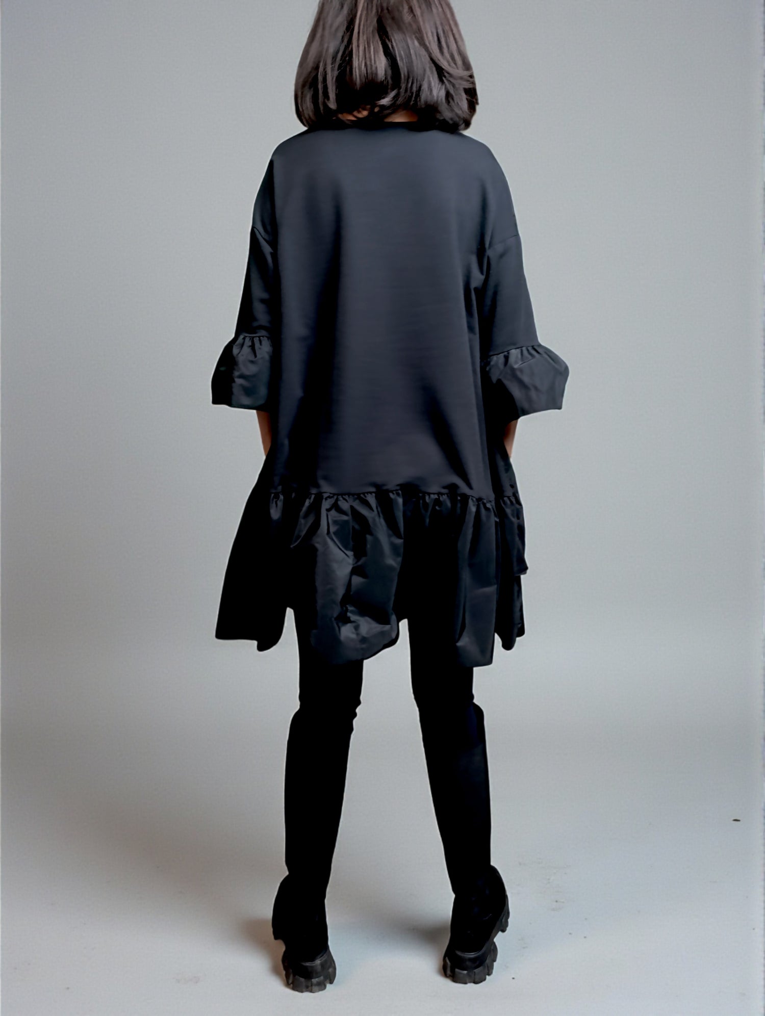 Vedere din spate a rochiei scurte cu umeri căzuți și croială lejeră, în nuanță neagră.