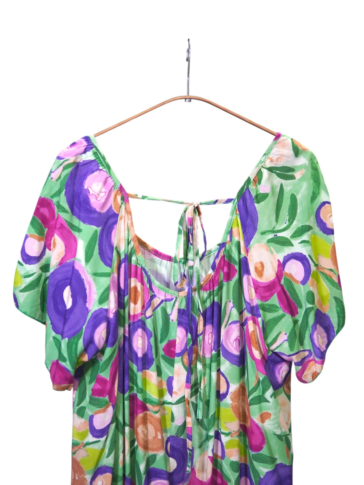 Detaliu spate cu fundă și decolteu adâncit pe rochie cu imprimeu floral viu colorat