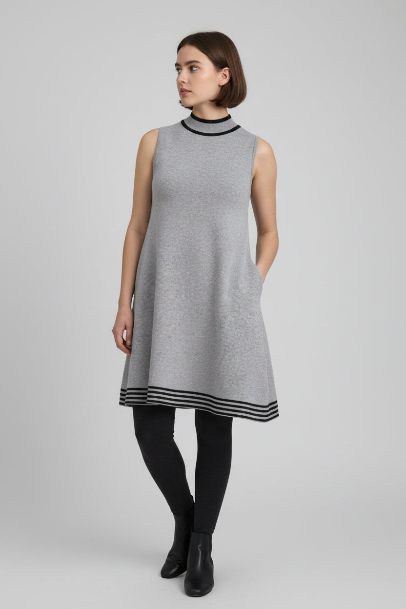 Rochie tricotată gri, fără mâneci, cu croială evazată și tiv decorativ în dungi contrast, purtată cu colanți negri.