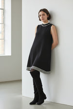 Rochie tricotată neagră, fără mâneci, cu croială lejeră și tiv cu dungi contrast, stil minimalist.