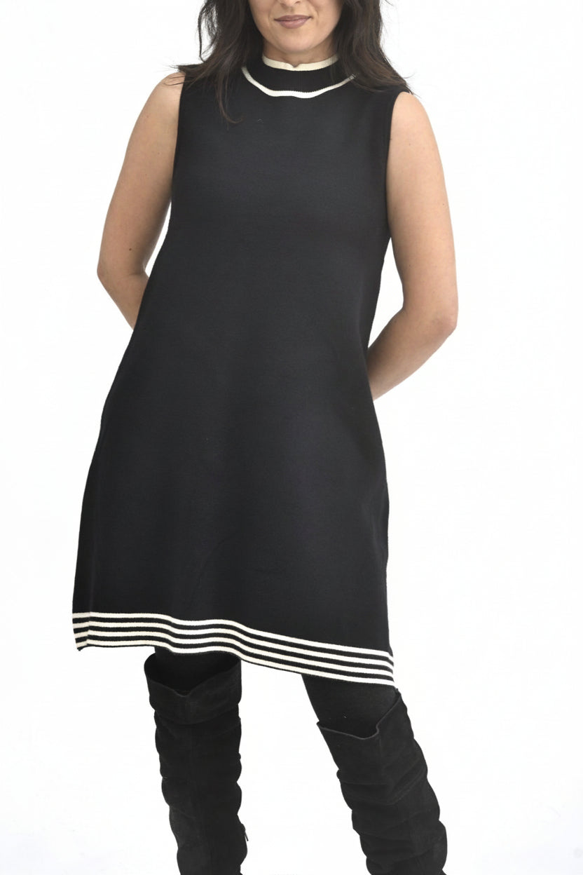 Rochie tricotată neagră, purtată cu cizme înalte, siluetă evazată și linie curată, potrivită pentru sezon rece.