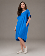 Rochie vaporoasă cu guler rotund, lejeră și ușor asimetrică, accesorizată cu floare roșie