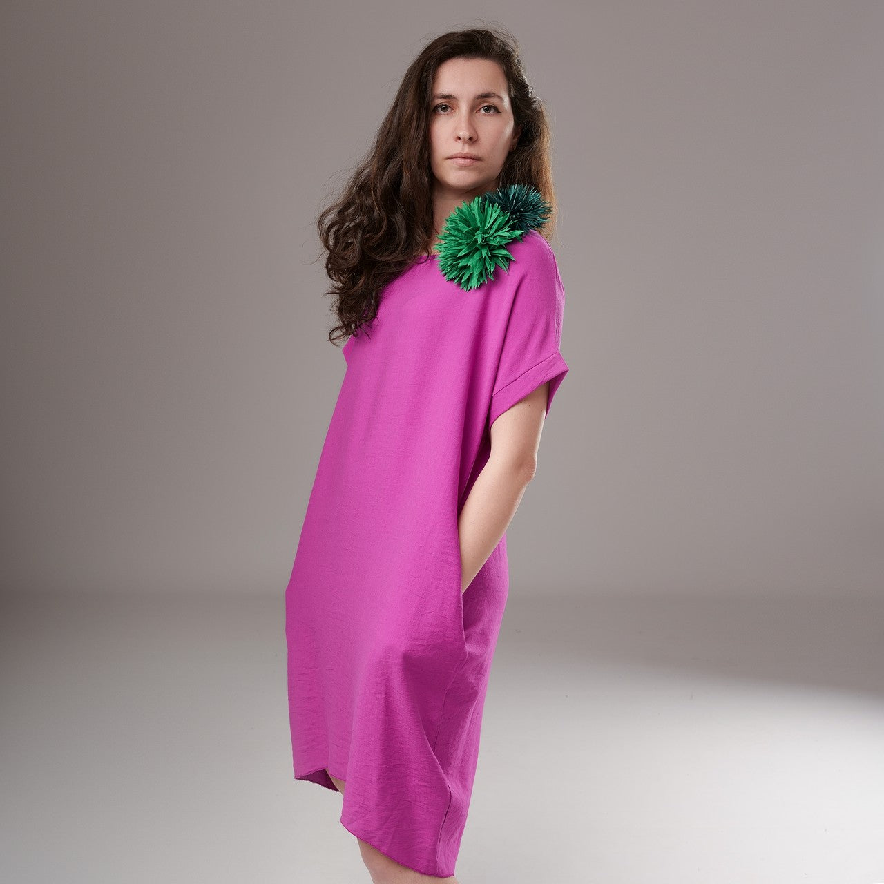 Rochie vaporoasă fucsia din viscoză, cu croială lejeră și mâneci scurte, purtată cu floare decorativă pe umăr