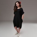 Rochie vaporoasă neagră cu guler rotund, lejeră și ușor asimetrică, accesorizată cu floare roșie

