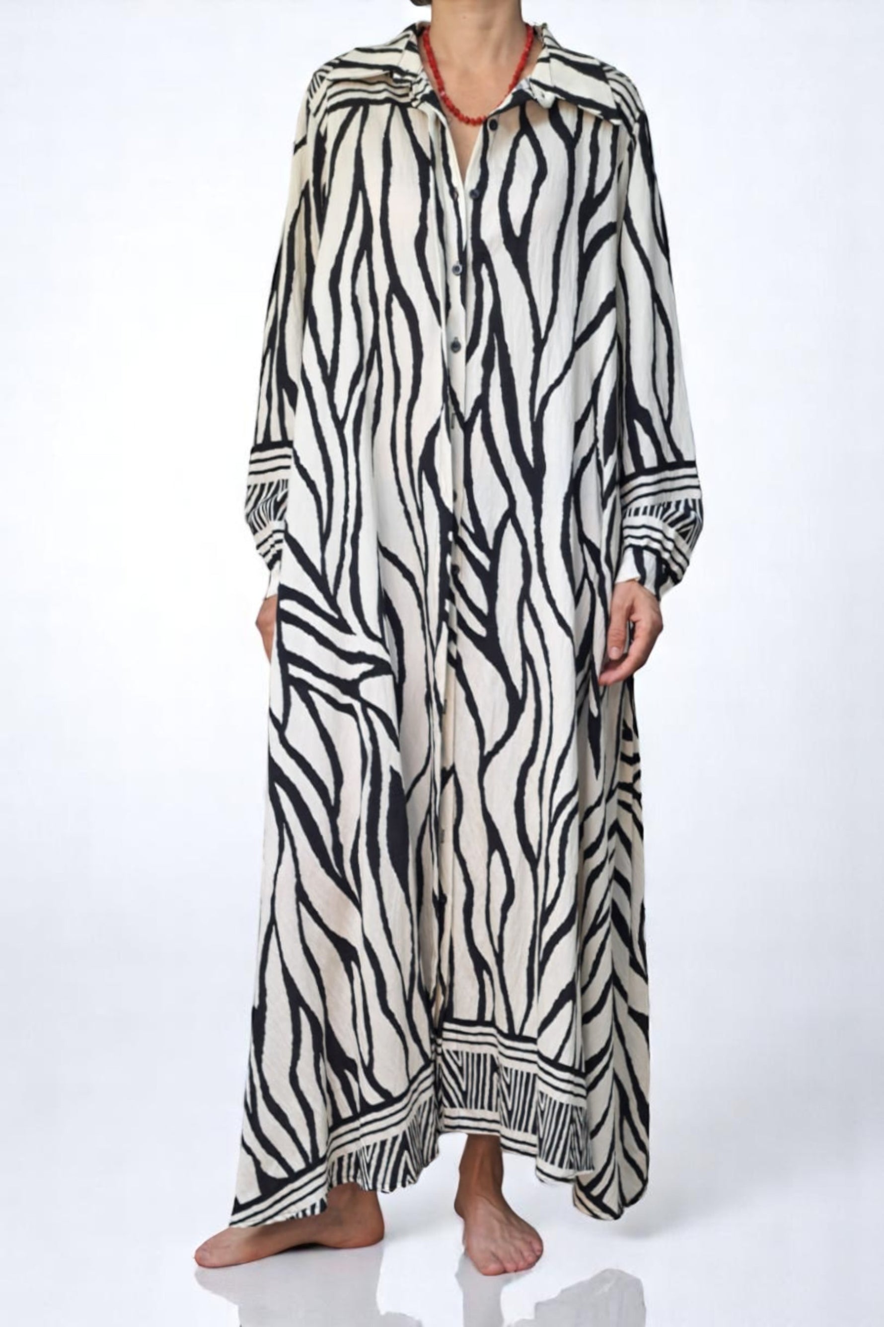Detaliu frontal al rochiei lungi cu imprimeu zebra, cu guler clasic și mâneci lungi largi, accentuând textura ușor creponată.