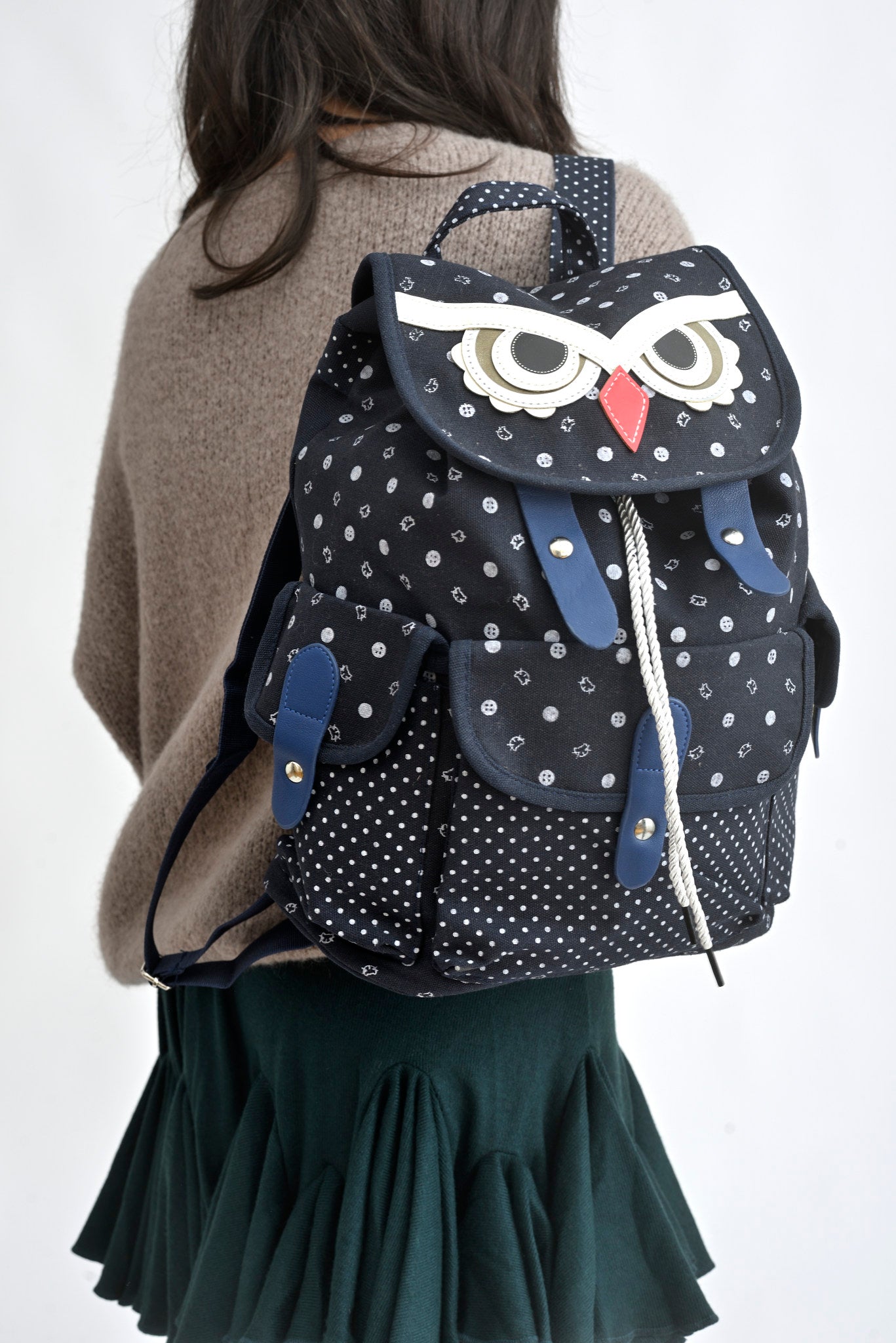 Detaliu de design rucsac bufniță bej, cu clapetă decorativă și buzunare frontale.