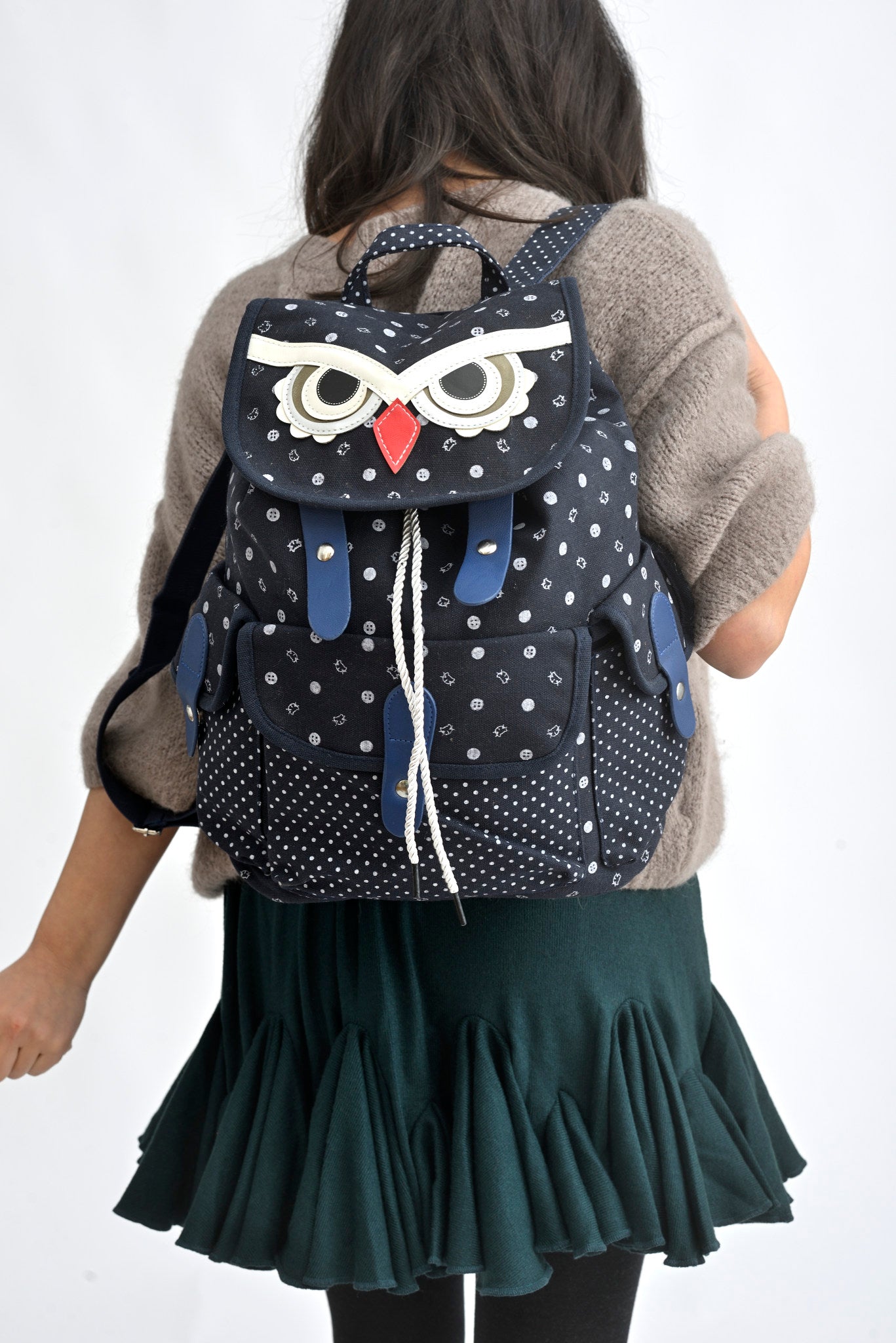 Rucsac bufniță bej din canvas, cu detalii contrastante, purtat într-o ținută de zi.