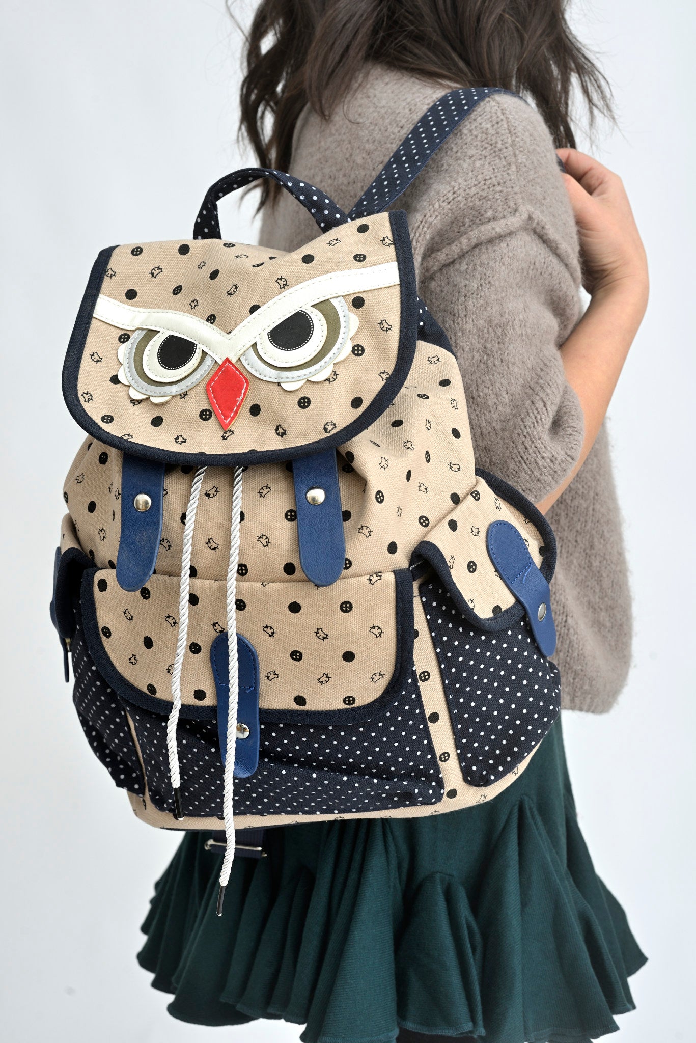 Rucsac tip bufniță din canvas bleumarin cu imprimeu, purtat pe spate într-o ținută casual.