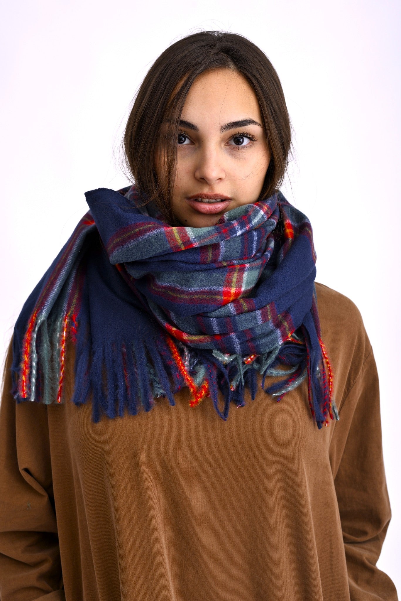 Șal gros în carouri bleumarin și roșu, purtat înfășurat lejer la gât peste un pulover maro.