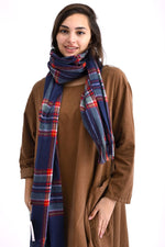 Șal lung în carouri bleumarin, roșu și verde, purtat drept peste umeri.