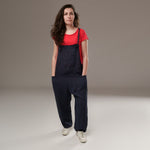 Salopetă lungă din in, culoare bleumarin, cu bretele reglabile și picior larg, purtată cu tricou roșu și teniși albi