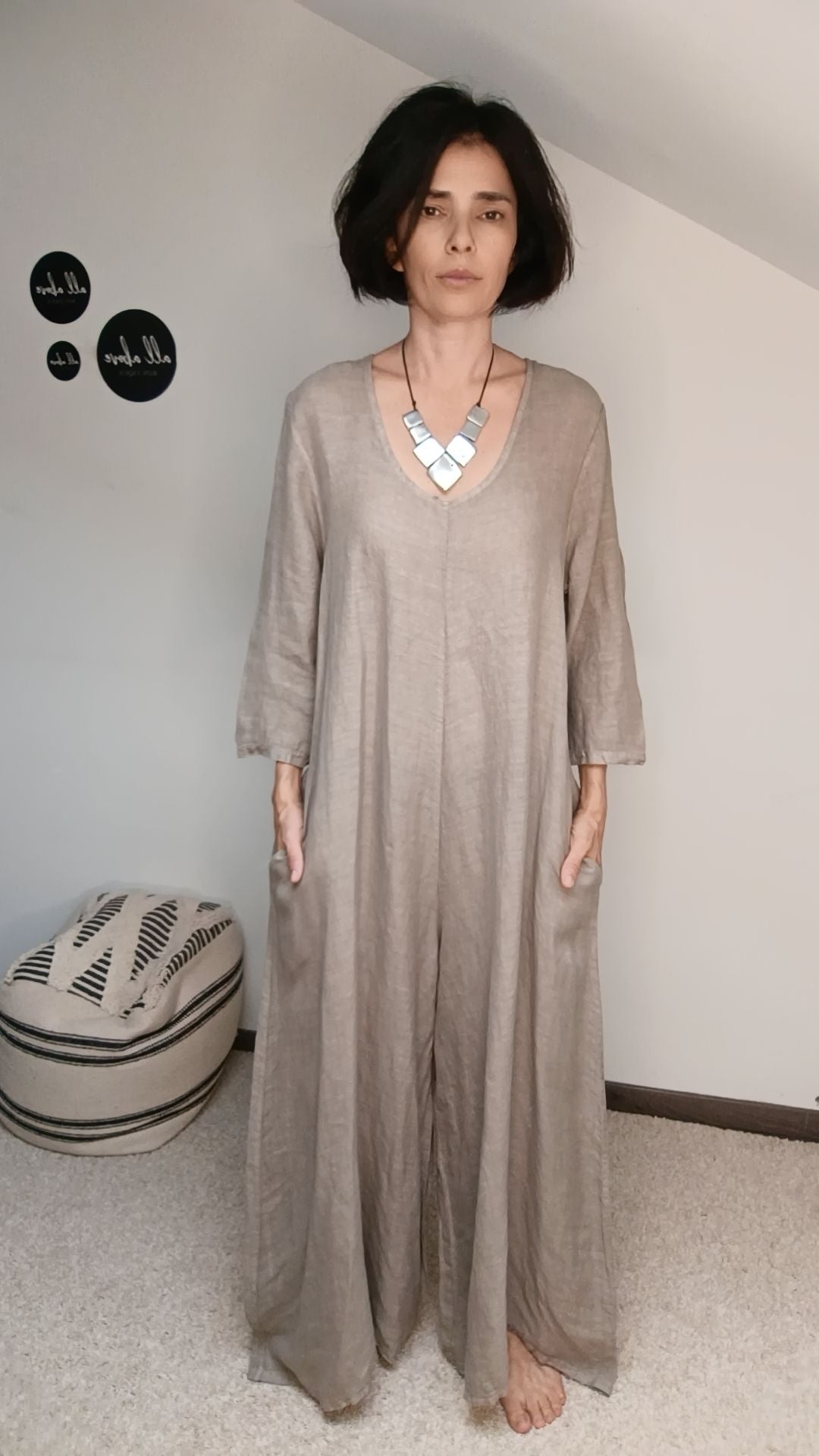  Salopetă bej din in purtată de model într-un spațiu interior, croială vaporoasă și lejeră.