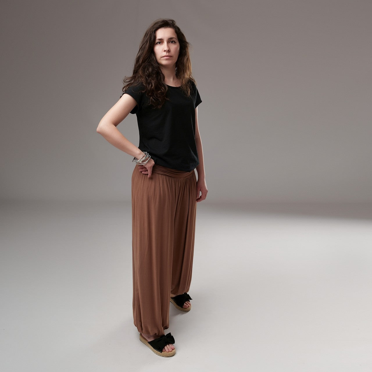 Șalvari cărămizii din bumbac cu talie drapată, purtați cu tricou negru, evidențiind silueta relaxată și croiala tip gogoșar.