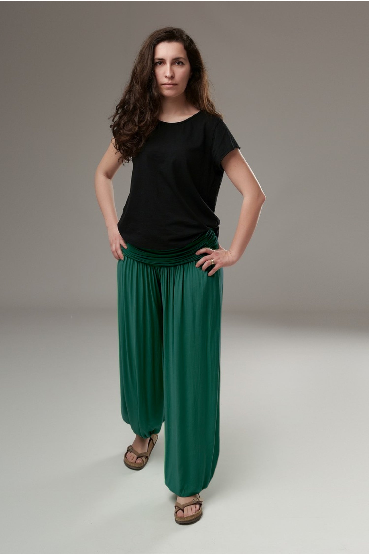 Pantaloni șalvari verzi, purtați cu tricou negru, prezentând forma amplă și flexibilitatea croielii.
