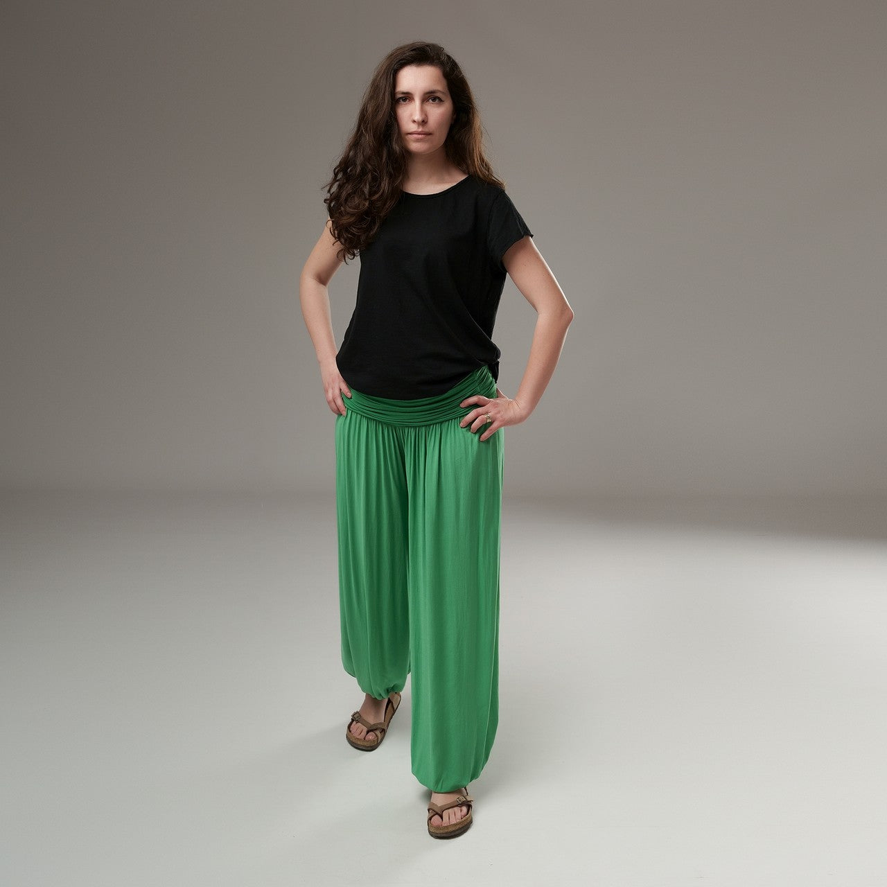  Pantaloni șalvari verzi, purtați cu tricou negru, prezentând forma amplă și flexibilitatea croielii.

