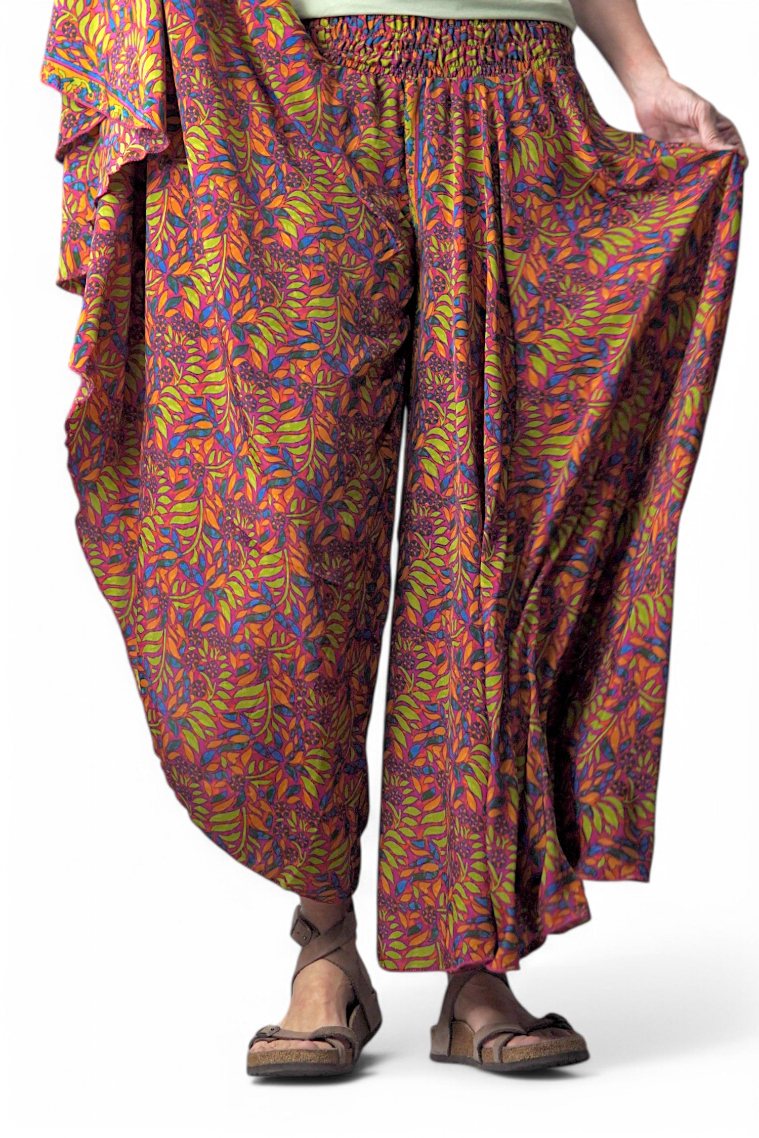 Șalvari colorați cu imprimeu floral în nuanțe vibrante de portocaliu, mov și verde, confecționați din material art silk, văzuți din față.