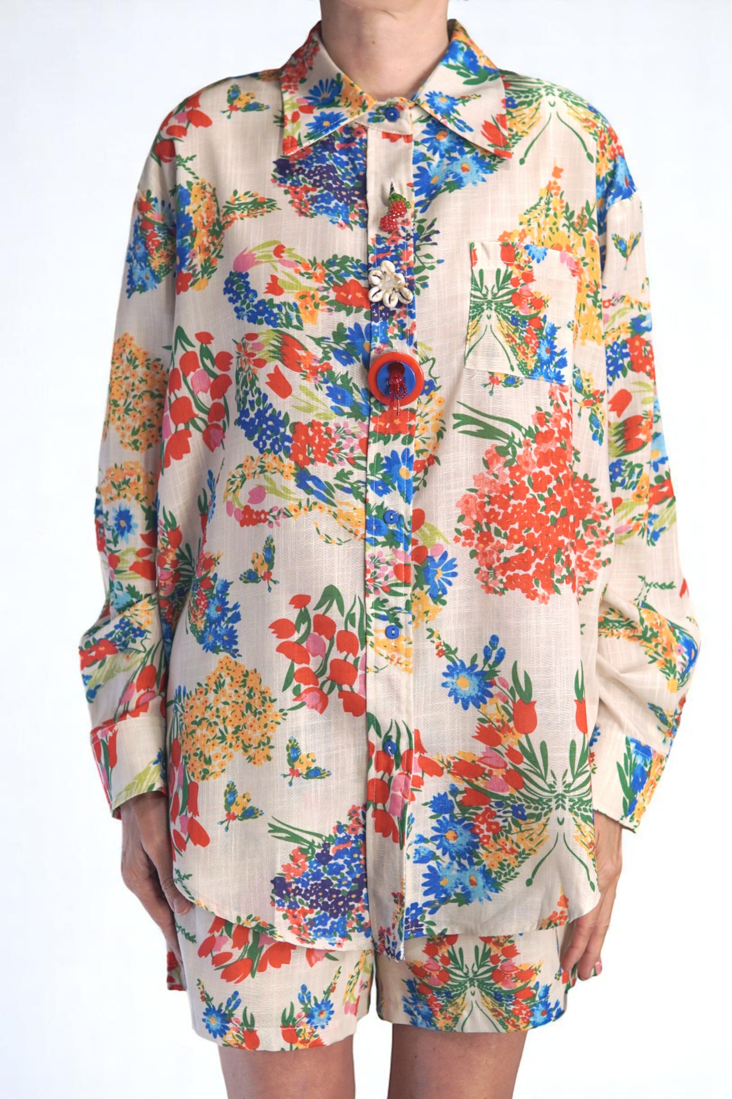 Cămașă lejeră cu imprimeu floral viu colorat, purtată cu pantaloni scurți asortați.