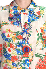 Detaliu al gulerului și nasturilor decorativi ai cămășii cu imprimeu floral multicolor.