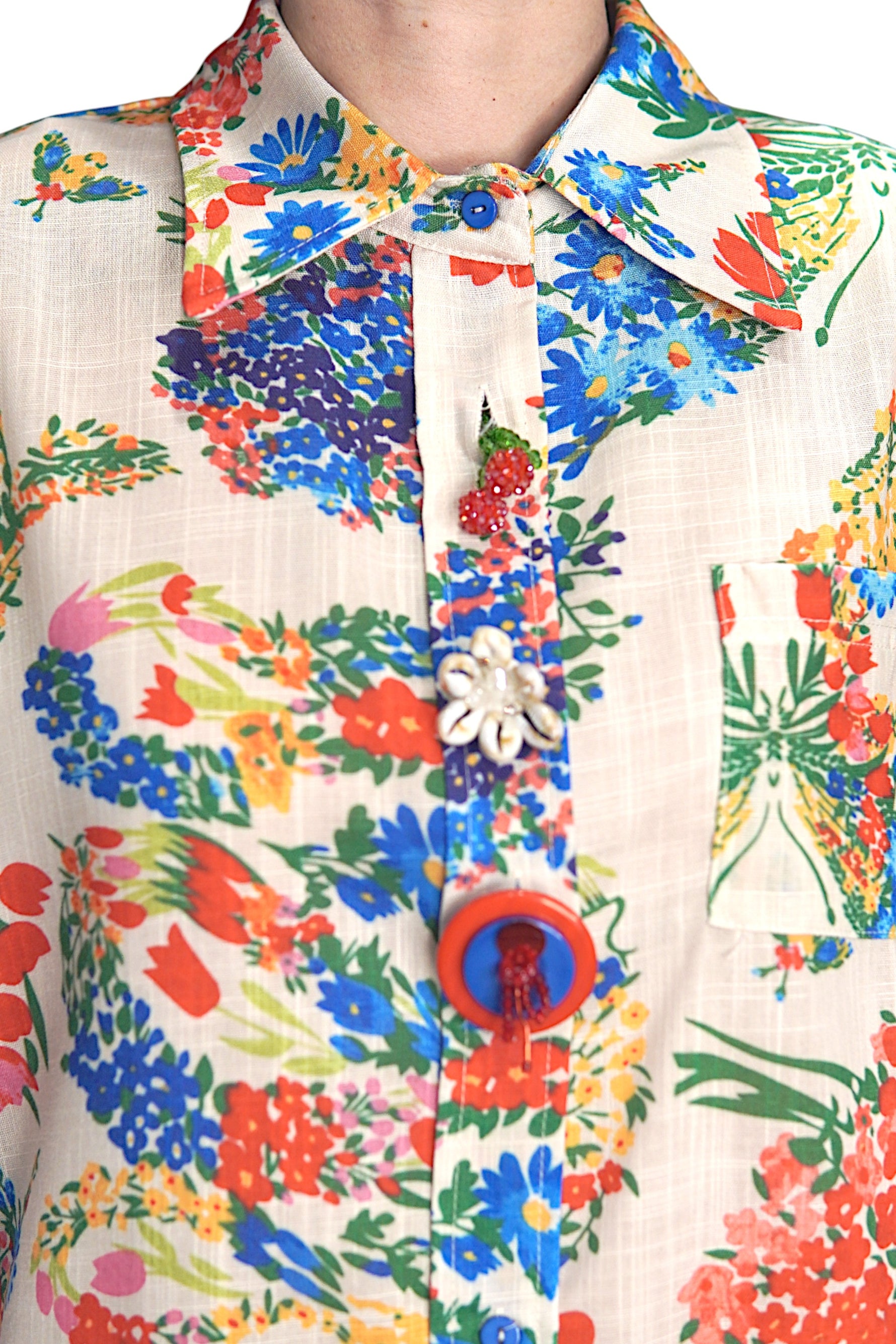 Detaliu al gulerului și nasturilor decorativi ai cămășii cu imprimeu floral multicolor.