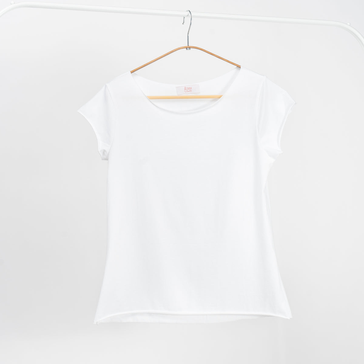 Tricou alb basic din bumbac cu mânecă scurtă și guler rotund, atârnat pe umeraș.