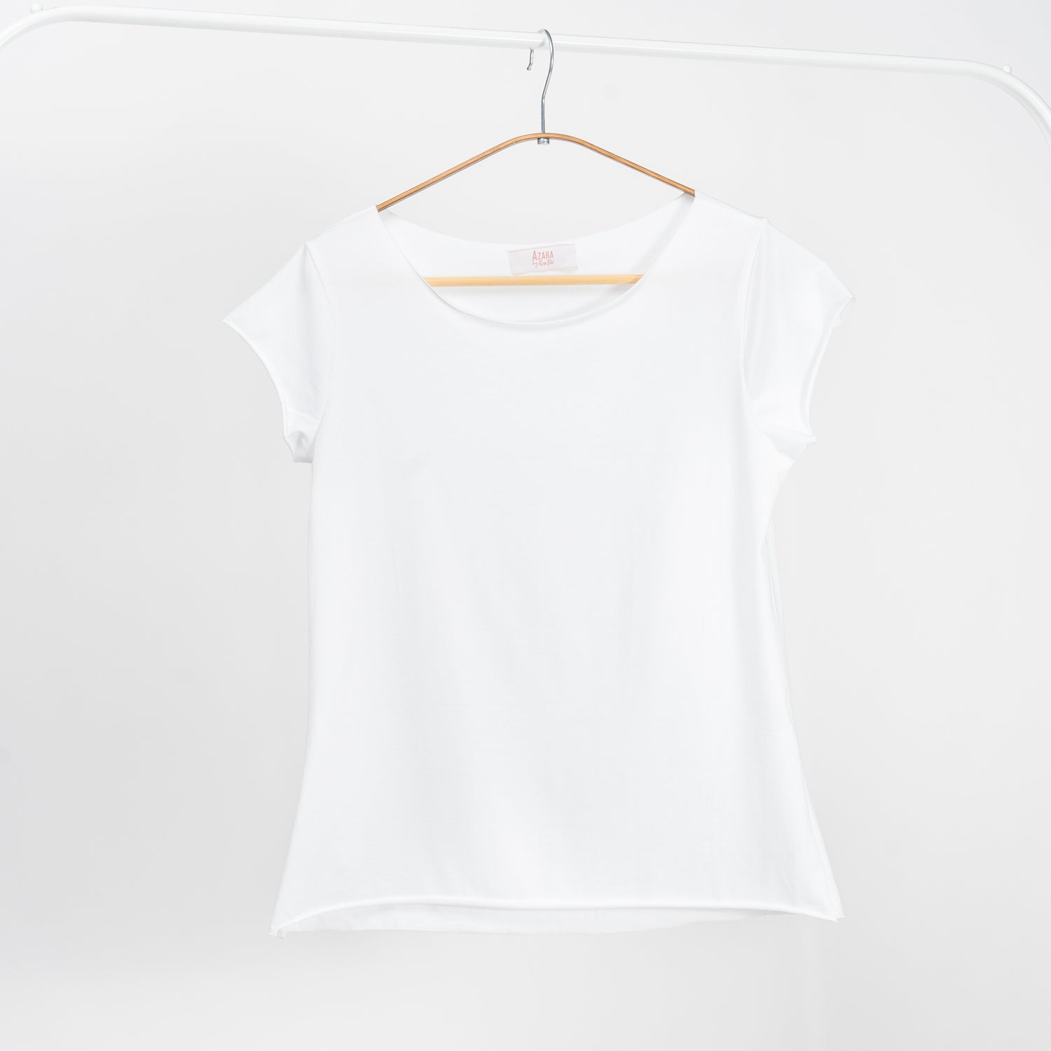 Tricou alb basic din bumbac cu mânecă scurtă și guler rotund, atârnat pe umeraș.