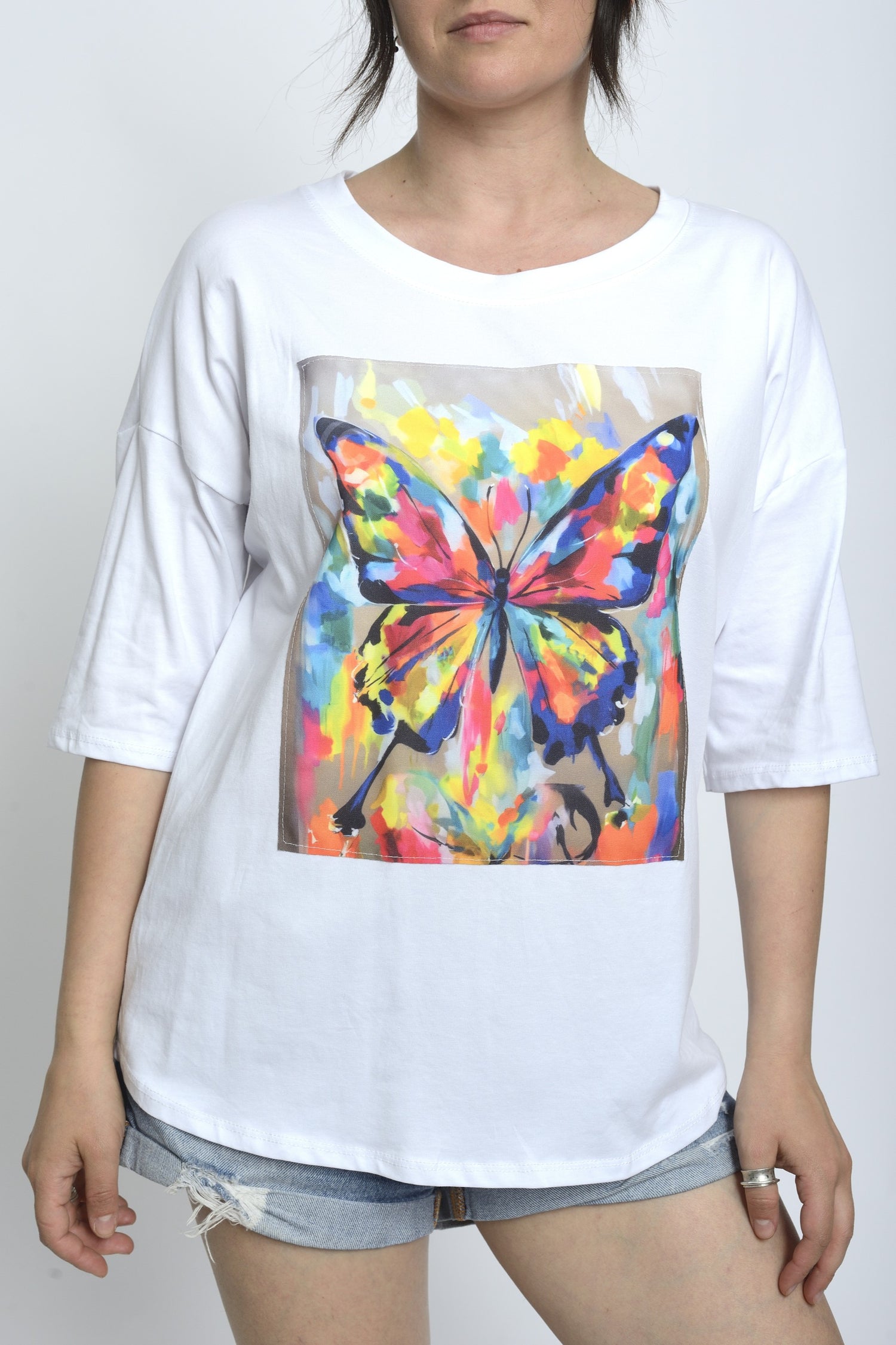 Tricou alb cu mânecă scurtă și imprimeu pictural înfățișând un fluture multicolor, purtat de model