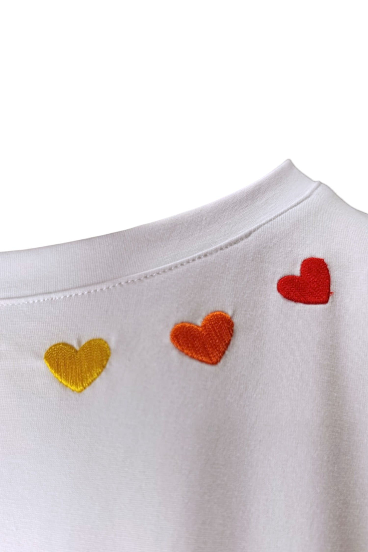 Detaliu broderie cu inimioare roșii, portocalii și galbene pe gulerul unui tricou alb