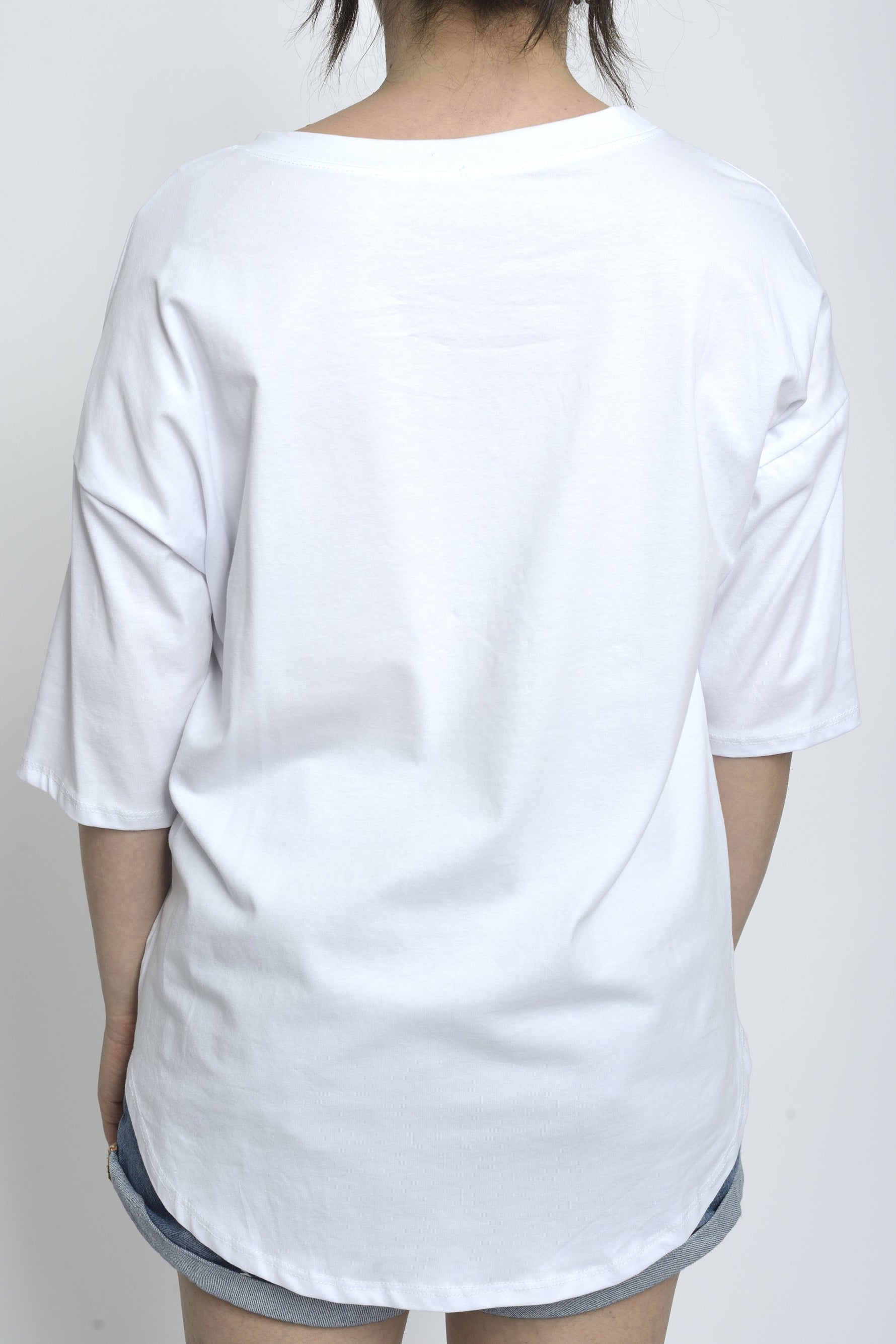 Spatele unui tricou alb simplu, fără imprimeu, cu croială lejeră