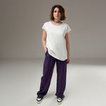 Tricou alb din bumbac, cu croială lejeră și margini rulate, purtat de model cu pantaloni mov.