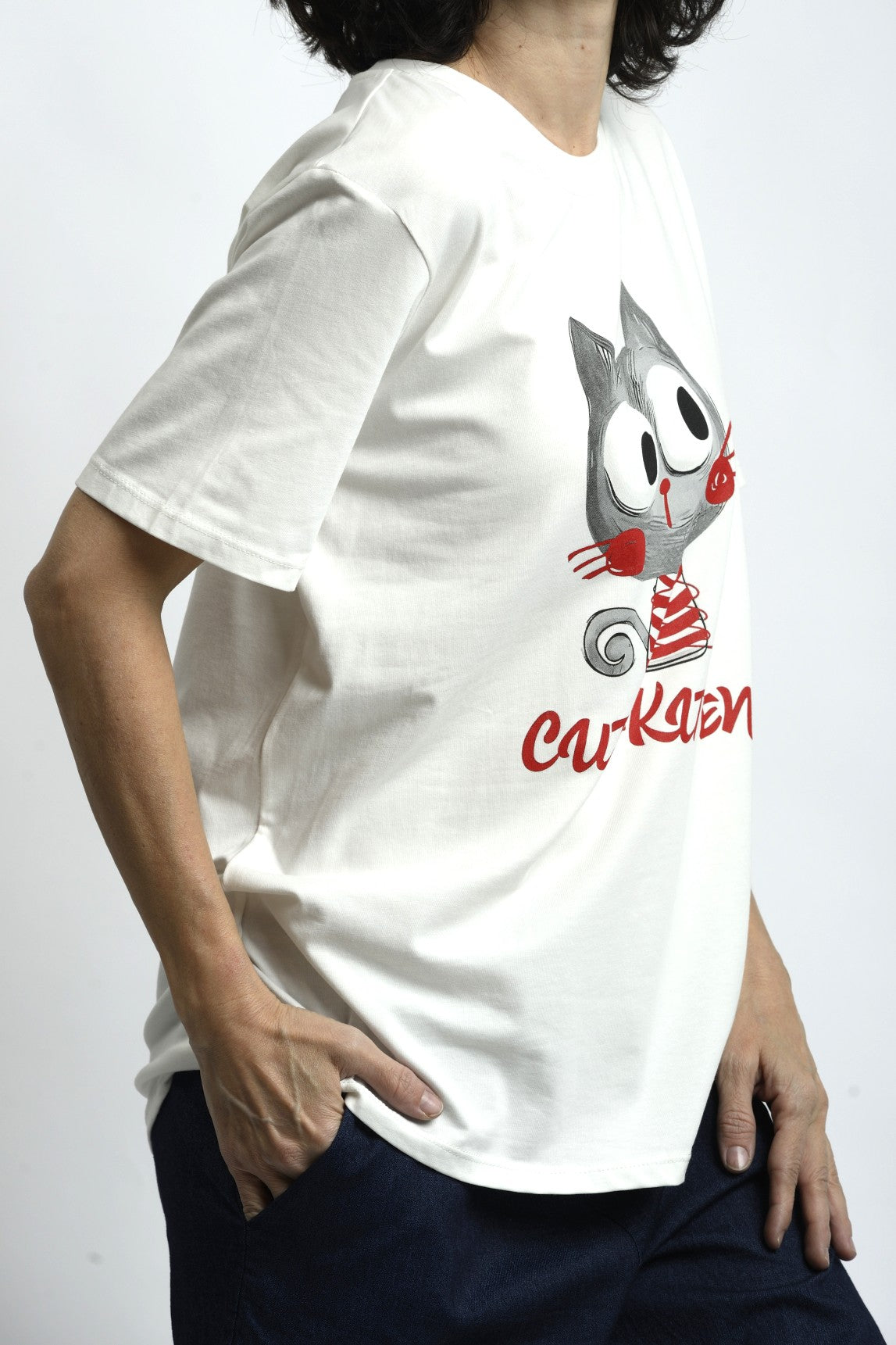 Vedere laterală tricou alb cu imprimeu pisicuță, material lejer și cădere naturală pe corp.