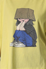 Prim-plan pe imprimeul colorat al tricoului galben oversized, cu o fată în pantaloni albaștri.