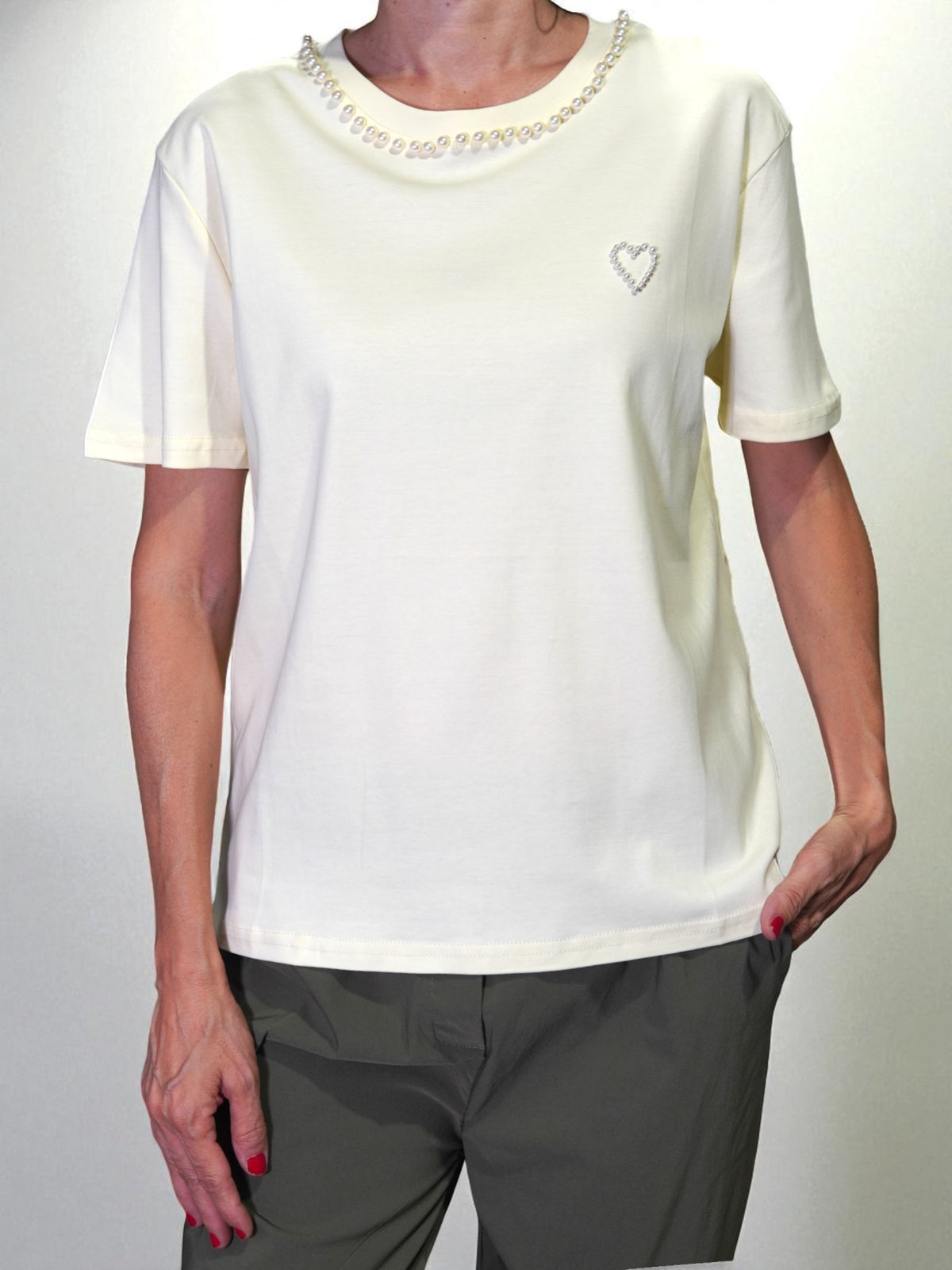 Tricou crem purtat de model, cu perle aplicate la guler și inimioară decorativă